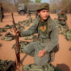 Army soldier looking away while crouching on land