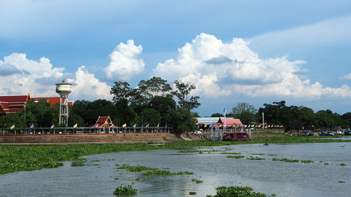 Scenic view of river by buildings against sky