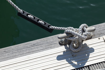 Close-up of rope tied on wood against sea