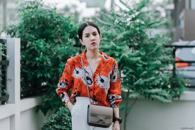 Portrait of woman standing against plants