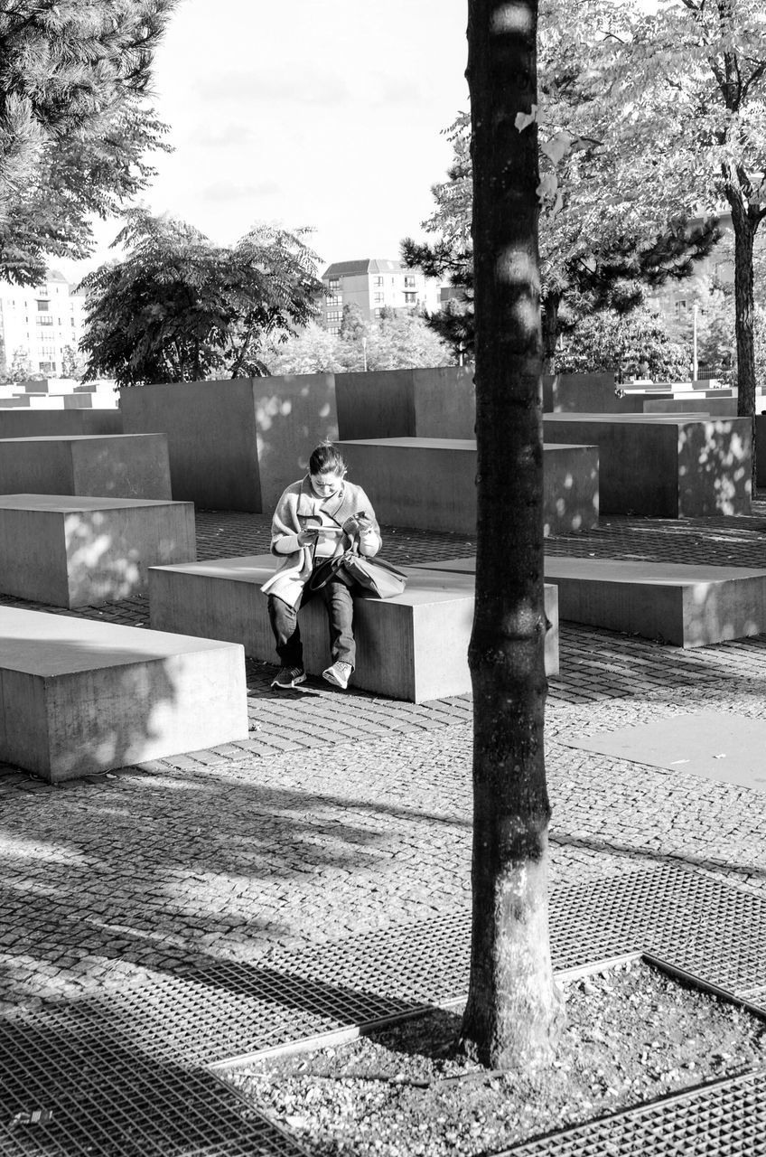 tree, building exterior, lifestyles, built structure, full length, leisure activity, architecture, rear view, sitting, city, railing, casual clothing, bench, relaxation, day, men, person, sunlight