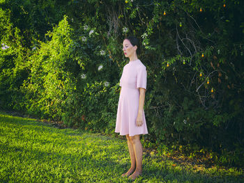 Woman in short pink dress in front of a hedge