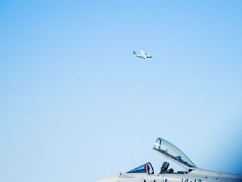 Low angle view of airplane flying against clear blue sky