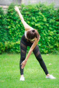 Rear view of woman with arms raised on field