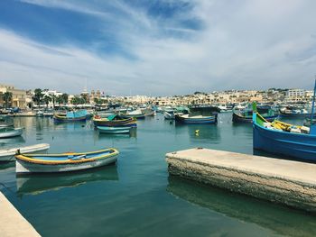 Boats moored at harbor against sky