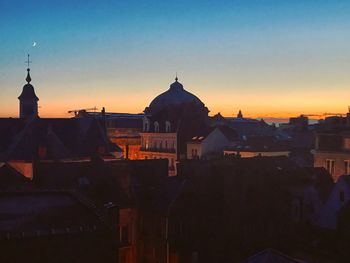 Buildings in town against sky at sunset