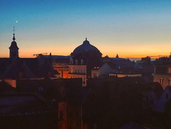 Buildings in town against sky at sunset