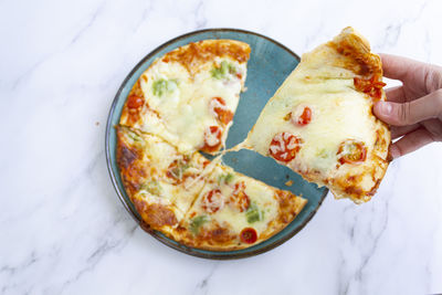 Top view of hand taking a slice of pizza