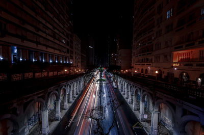 Illuminated street amidst buildings in city at night