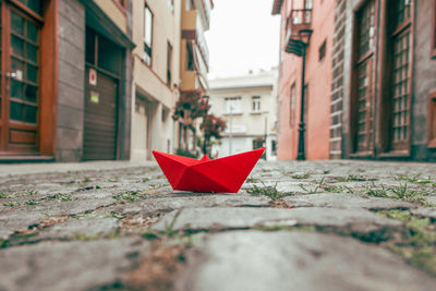 Close-up of red umbrella on street amidst buildings in city