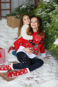 Portrait of smiling young woman sitting on snow