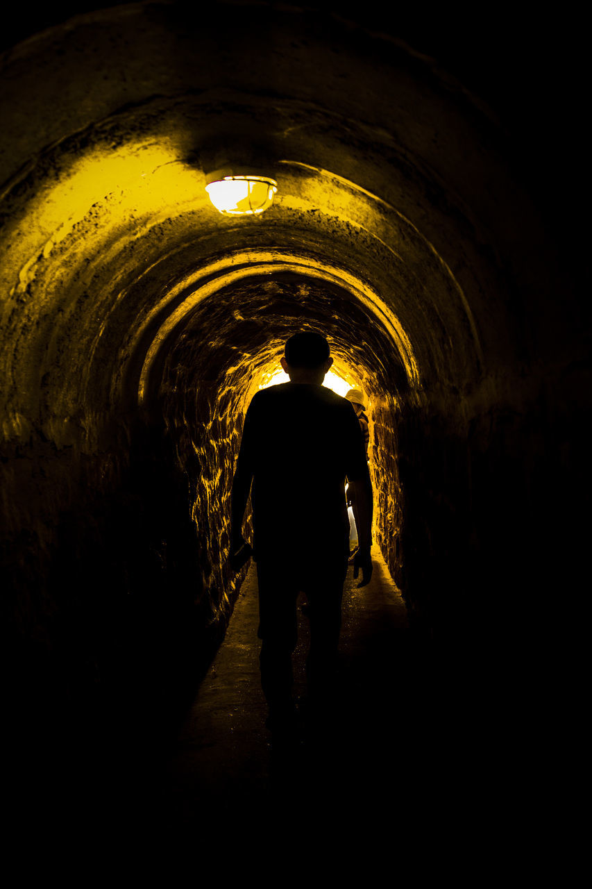 SILHOUETTE OF MAN STANDING IN TUNNEL