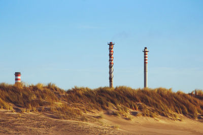 Chimneys of a factory behind some sand dunes