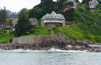 House by sea against trees and houses