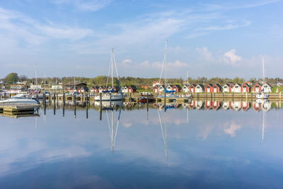 Sailboats moored at harbor against sky