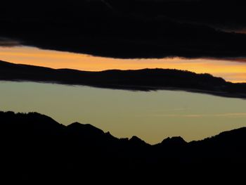 Scenic view of silhouette mountain against dramatic sky during sunset