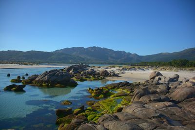 Scenic view of rocks and lake against clear blue sky