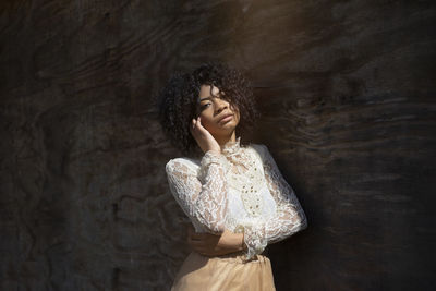 Portrait of a young african american woman next to a wooden wall