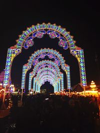 Low angle view of illuminated carousel against sky at night