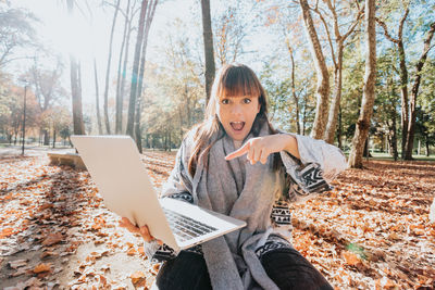 Young woman using laptop while sitting on field