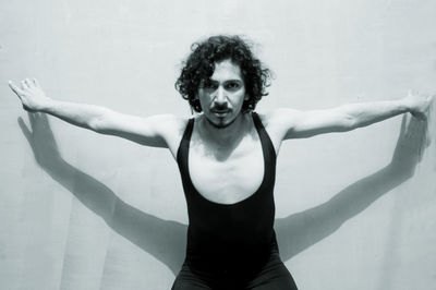 Portrait of mature man with arms outstretched standing against wall