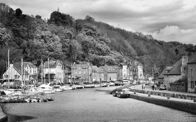 Sailboats in canal amidst buildings in city against sky
