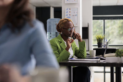 Side view of woman using mobile phone while sitting in cafe