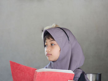 Cute muslim girl wearing hijab and reading book