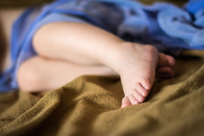 Low section of child lying on bed at home