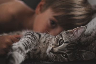 Close-up portrait of boy and cat lying on bed