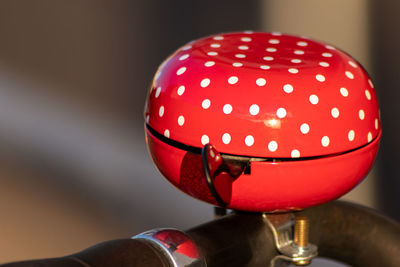 Red bike bell with white polka dots in evening sunshine and blurred background for healthy mobility