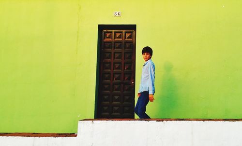 Teenage boy against green wall