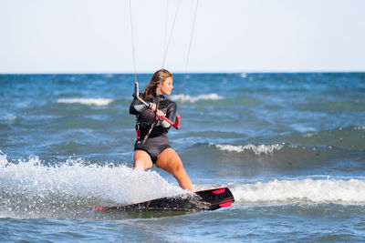 Full length of woman surfing in sea against sky