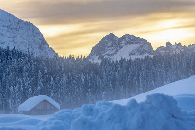 Snow covered landscape against sky during sunset