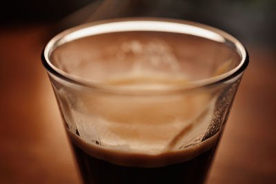 Glass with hot espresso coffee on wooden table closeup