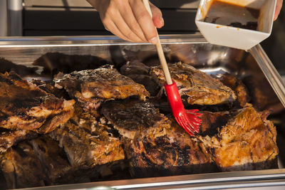 Cropped image of person basting barbecue ribs