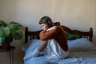 Rear view of woman sitting on bed at home