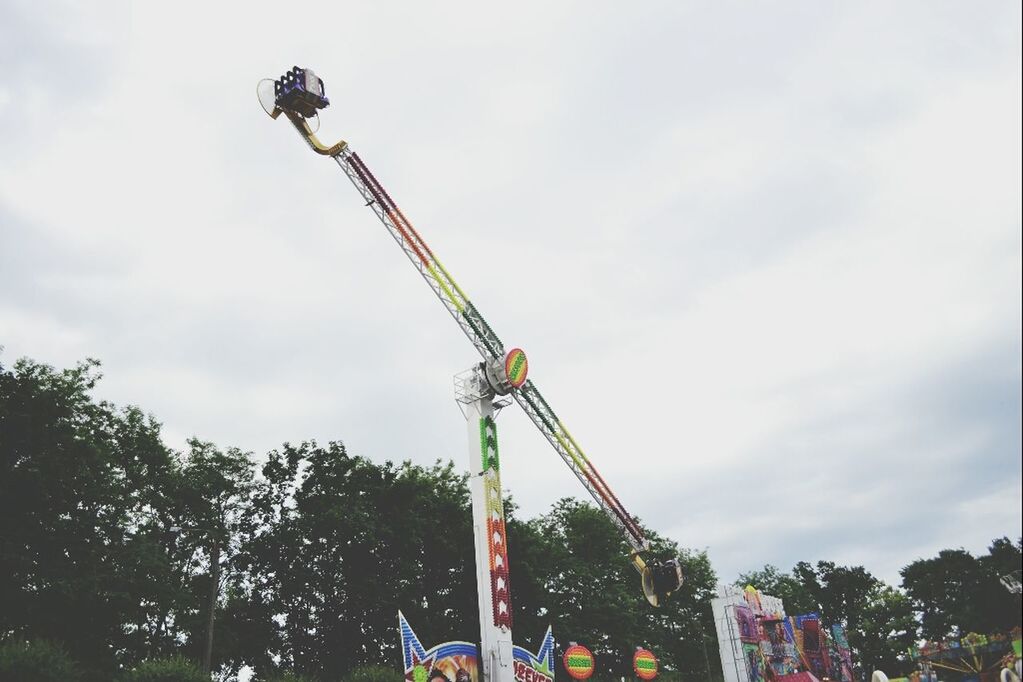 low angle view, sky, amusement park, amusement park ride, cloud - sky, tree, arts culture and entertainment, cloudy, leisure activity, tall - high, fun, ferris wheel, cloud, built structure, day, enjoyment, outdoors, street light, lighting equipment