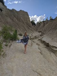 Rear view of woman on rock formation against sky