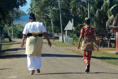 Rear view of mother with daughter walking on road