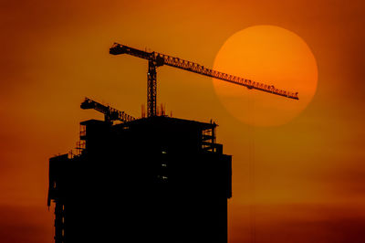 Low angle view of silhouette crane against sky during sunset