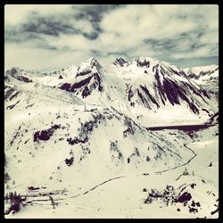 Scenic view of snow covered mountains against cloudy sky