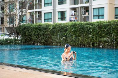 Woman in swimming pool by building