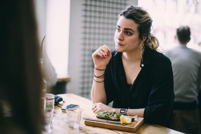 Young woman sitting on table at restaurant