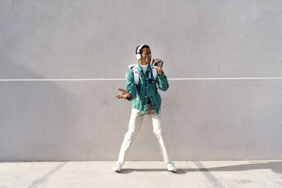 Full length of young man standing against wall