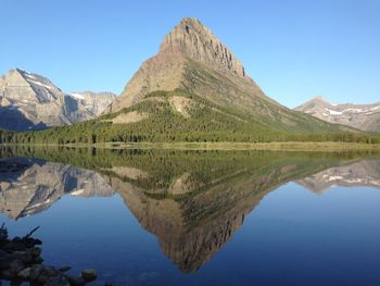 Scenic view of lake and mountains against clear blue sky