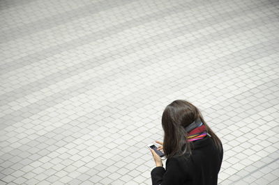 Rear view of woman using mobile phone on walkway