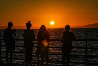 Silhouette people standing at beach during sunset