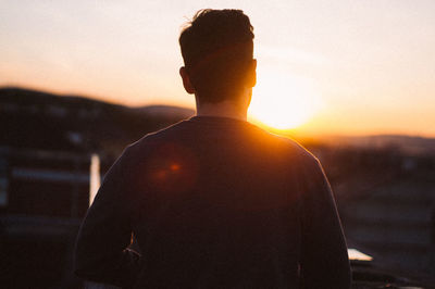 Rear view of silhouette man standing against sky during sunset