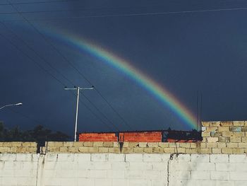 Low angle view of rainbow over wall against sky